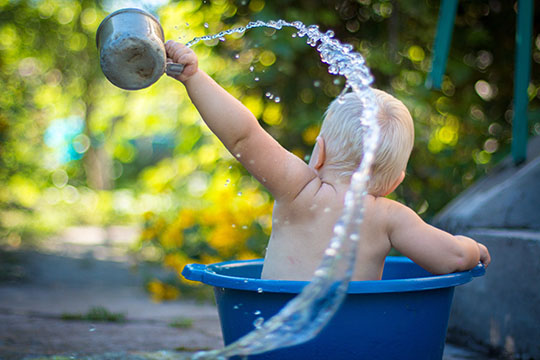 A baby in a bucket playing with water