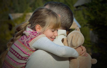 A young girl is giving a hug to her father