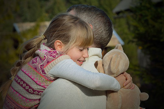A young girl is giving a hug to her father