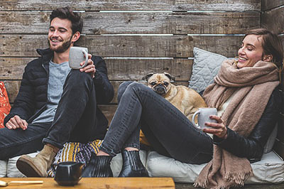 Two people are relaxed with a dog in a cabin