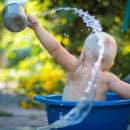 A baby in a bucket playing with water